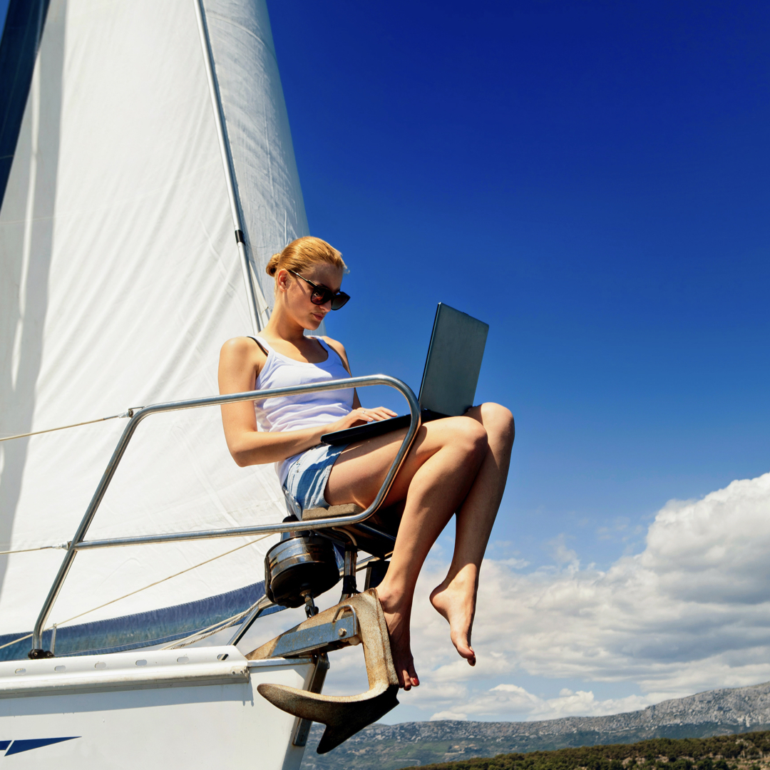 woman in shorts on a boat reading her laptop