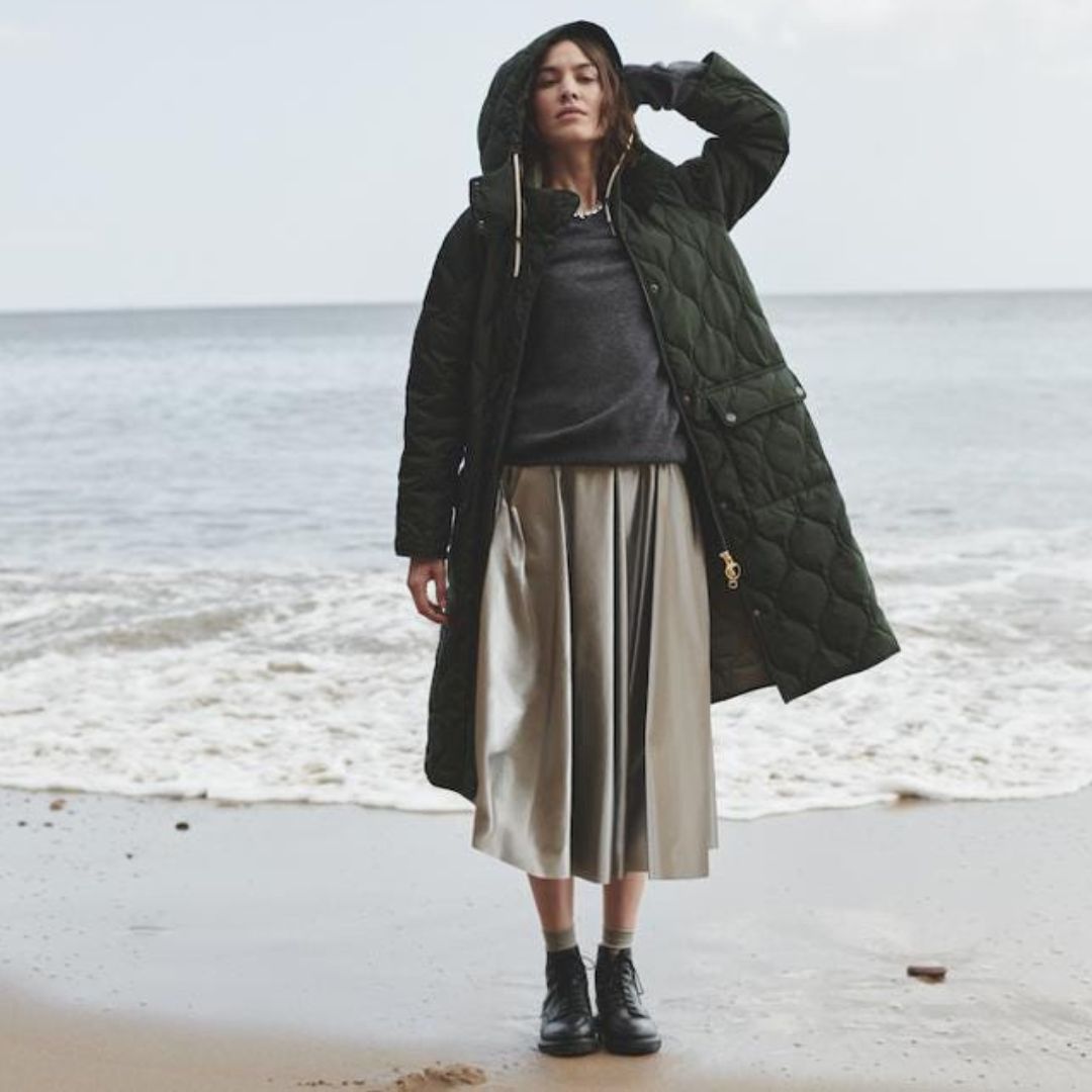 alexa chung wearing a skirt, pullover and a barbour coat at the sea in england