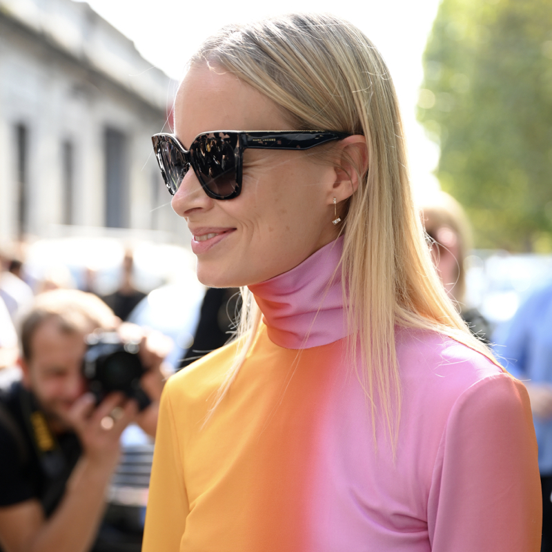 Stylish woman during Fashion Week wearing a pink and orange turtleneck and dark sunglasses.