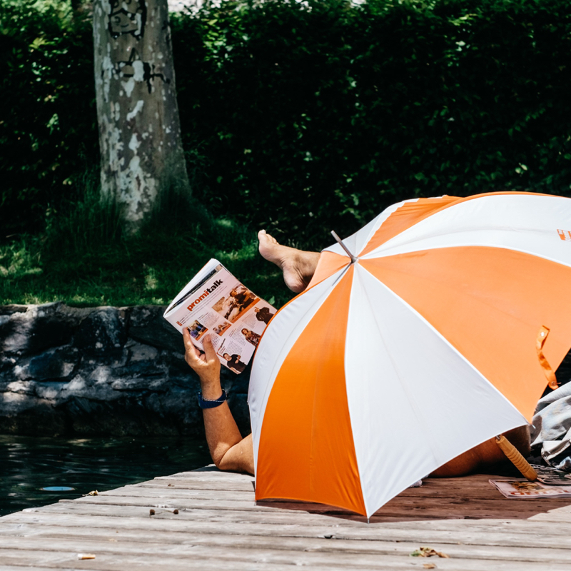Guy laying down under a sun umbrella in a lake in Klagenfurt, Austria