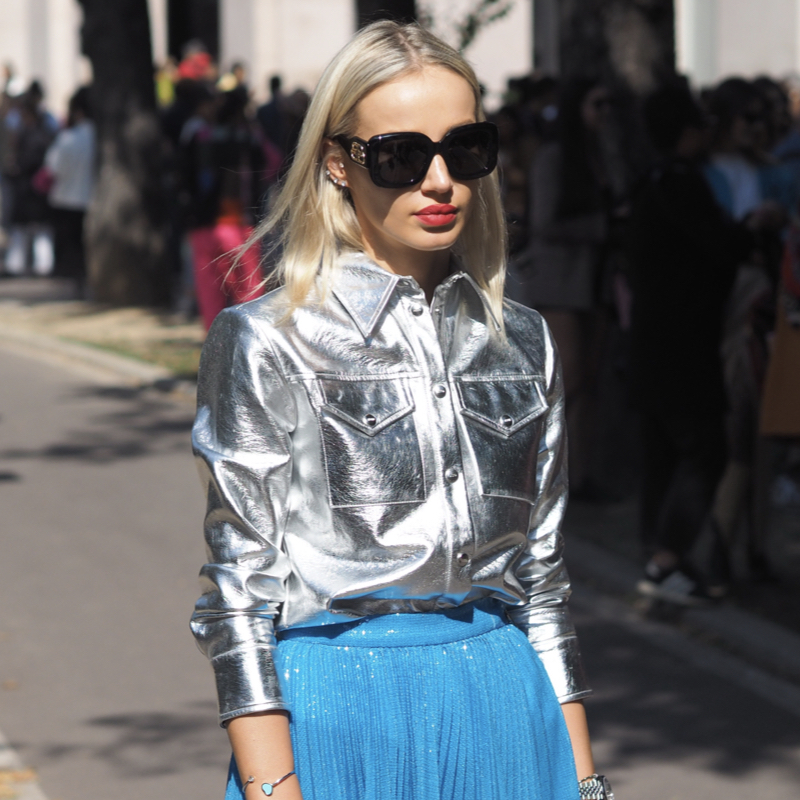 Street style photo of woman wearing a metallic shirt and plissé skirt, perfect for fall.