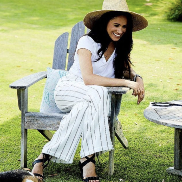 Meghan Markle wearing Anine Bing striped pants paired with a white t-shirt, sandals and a straw hat.