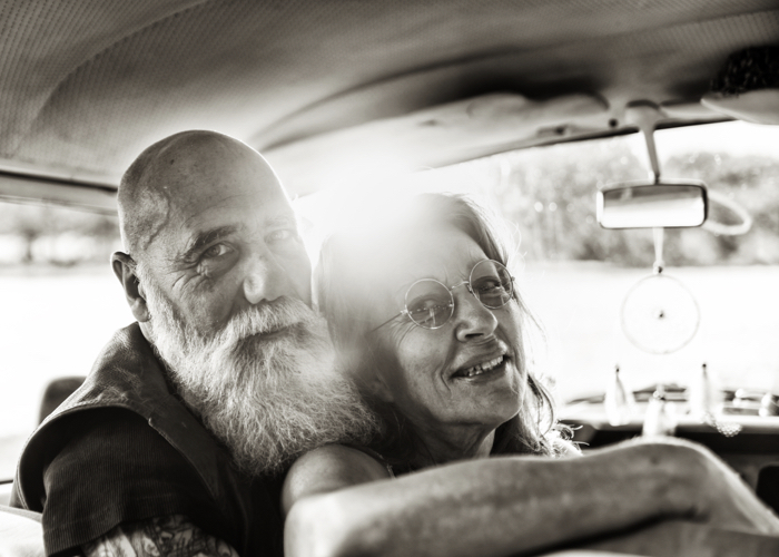 vintage photo showing a old couple in the car, looking at the camera and smiling, showing how they are happy together