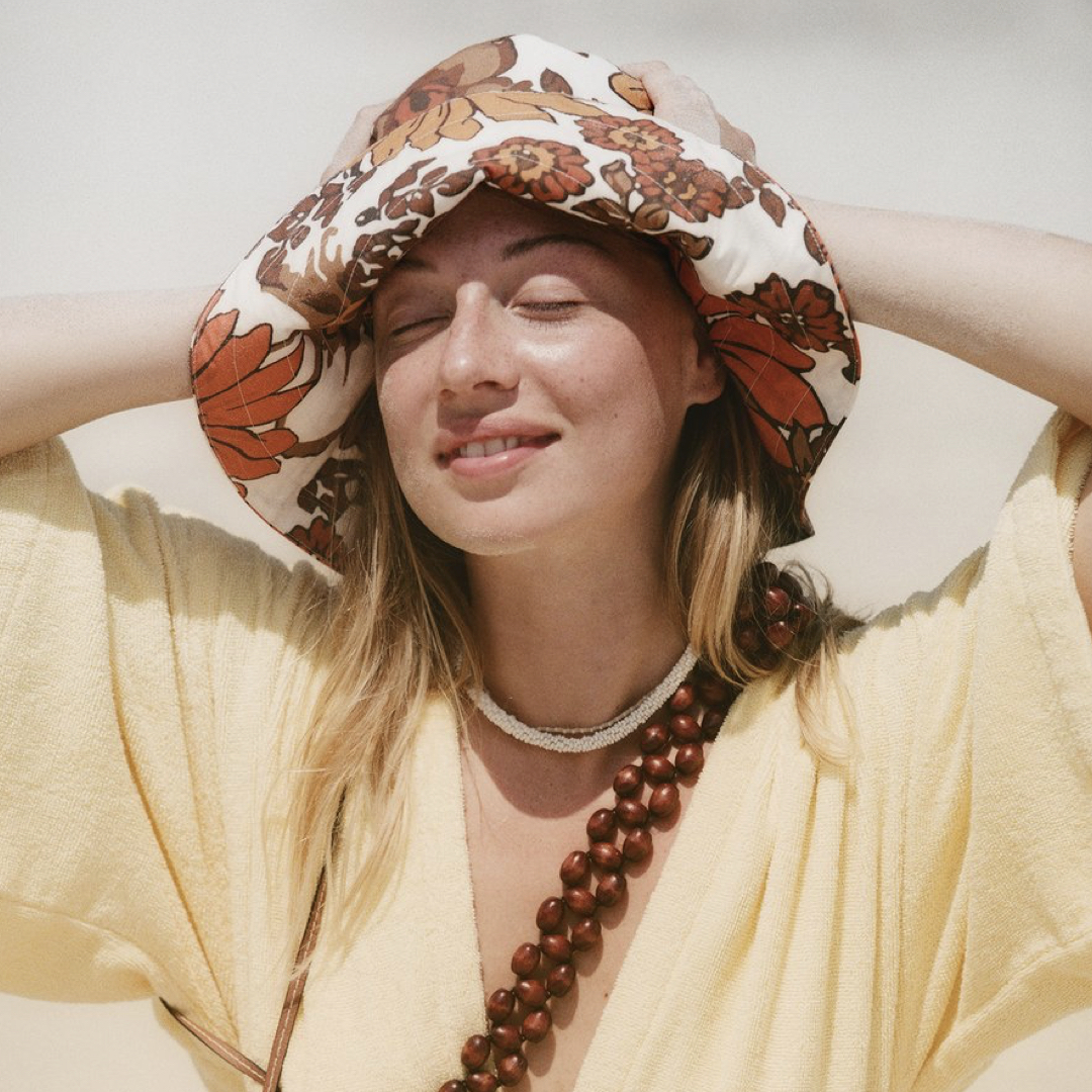 Woman wearing floral hat and a towel fabric kimono by Terry Towelling, the summer 2021 cloth trend.