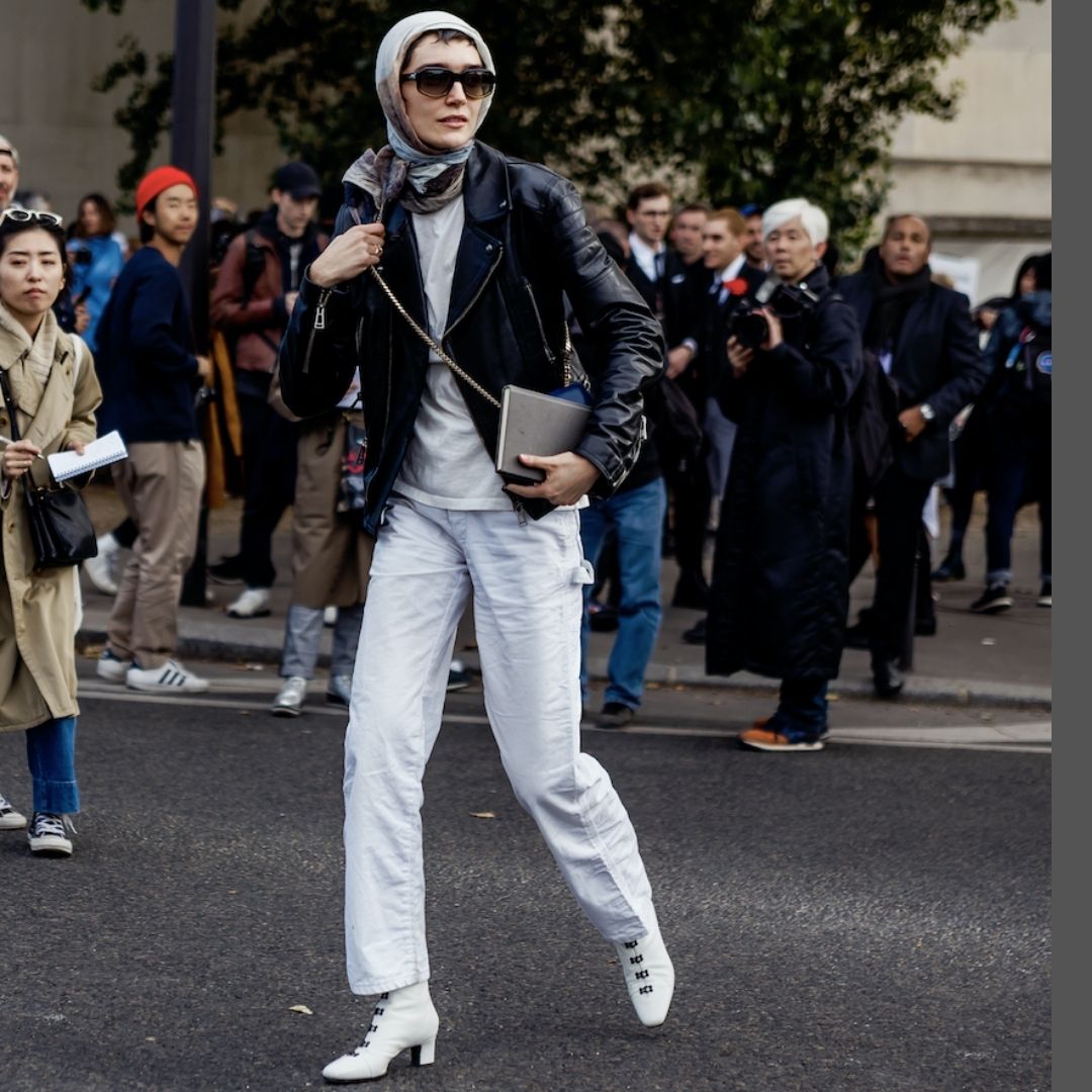 Woman pair biker jacket and scarf to make white jeans look more expensive.