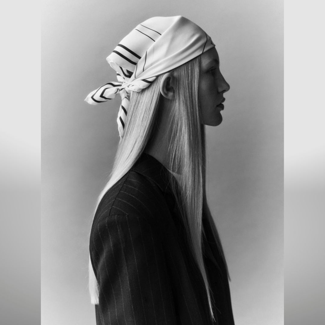 photo black and white of a model wearing a pinstripe suit headscarf, long straight hair and a
