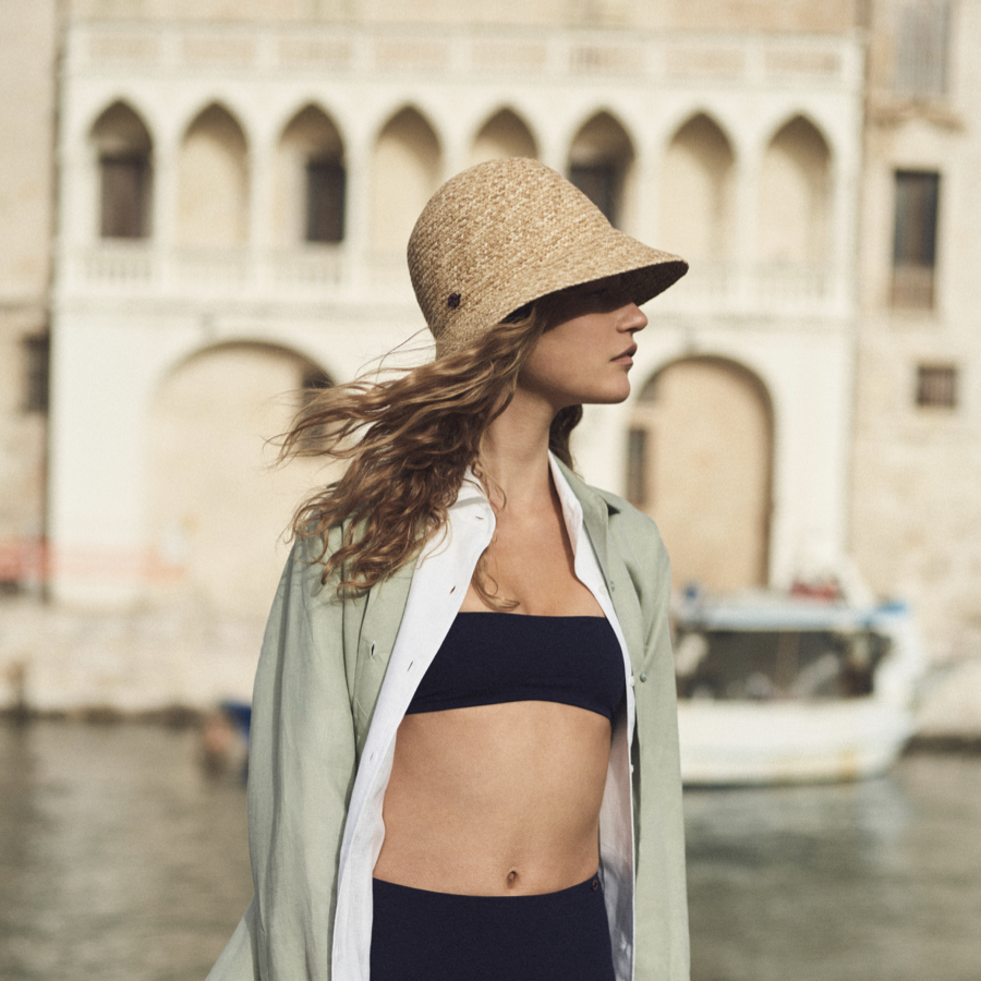 Woman on a summer vacation trip wearing hat and swimwear from her capsule wardrobe.