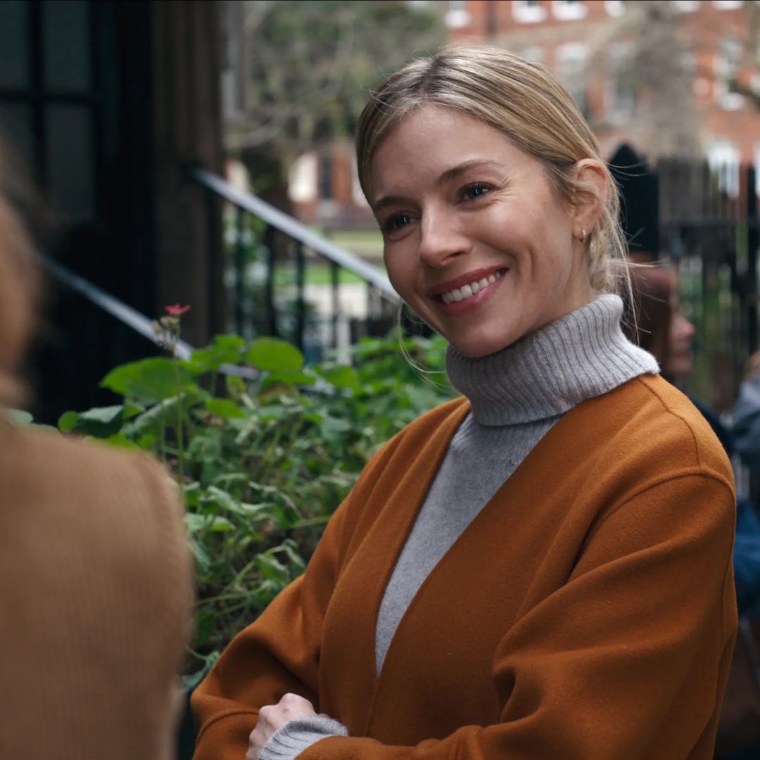 Sienna Miller wears a classic grey turtleneck paired with an ocre coat in one of the scenes of Anatomy of a Scandal