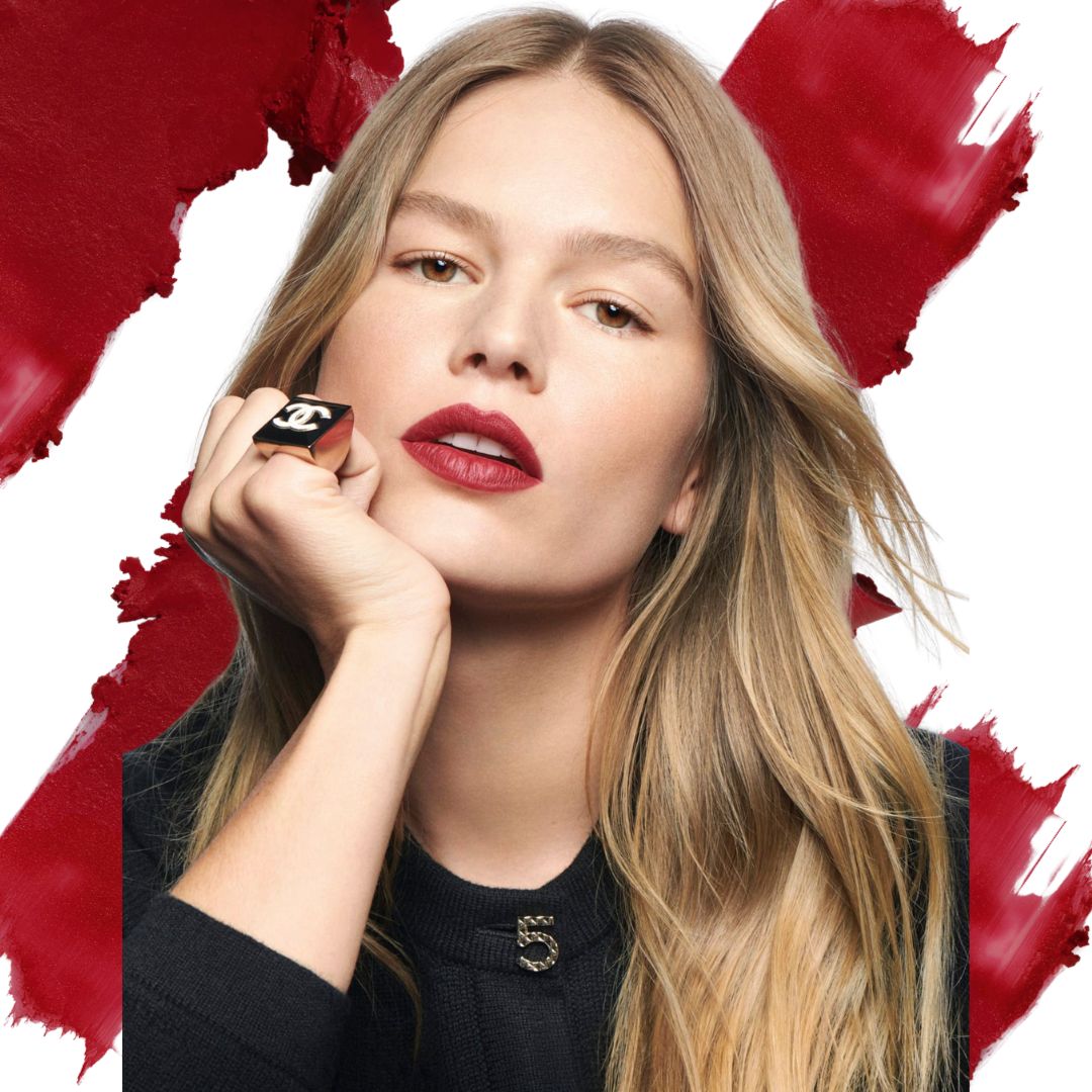 portrait of a blonde model wearing a black cardigan, a ring in the pinky finger and a bold red lipstick