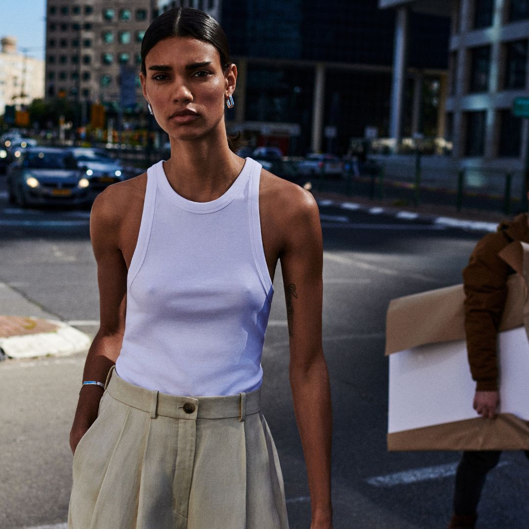 COS model wearing a white tank top and pleated pants in the streets of Nova York