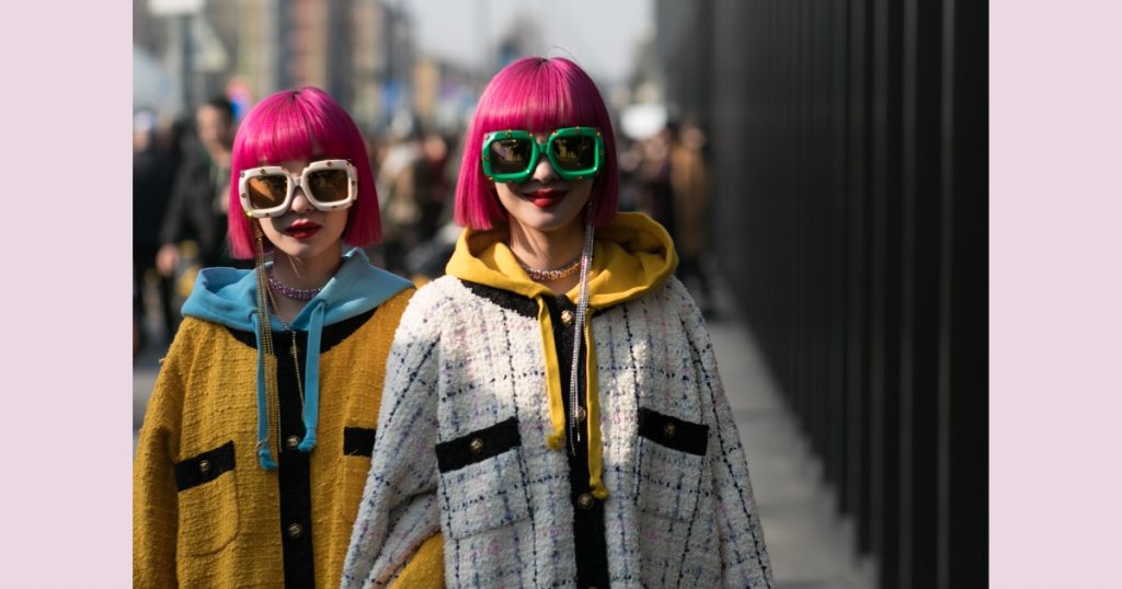 two fashionistas in Paris wearing pink hair and bold sunglasses