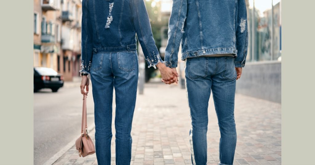 couple holding hands while walking in the streets and both are wearing a all-denim outfit