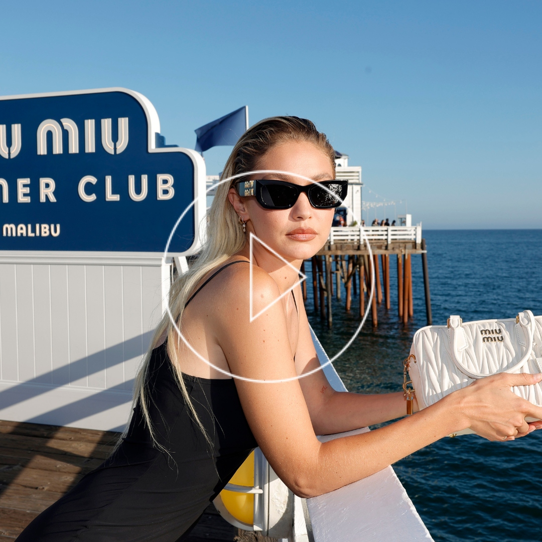 Gigi Hadid on the Malibu Pier wearing a black dress and white bag from Miu Miu