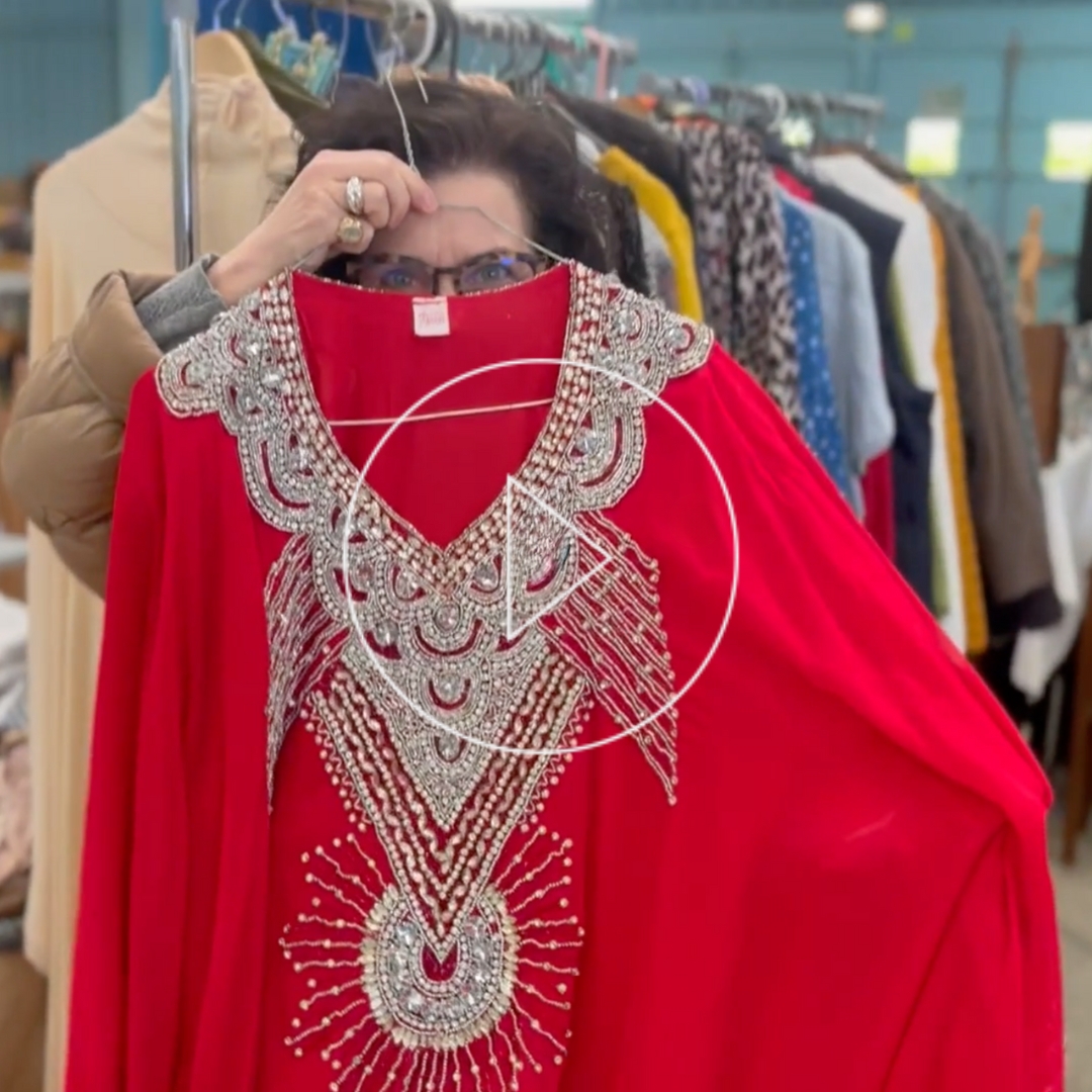 A woman show to the camera a red embroidered caftan from a French Vintage sales