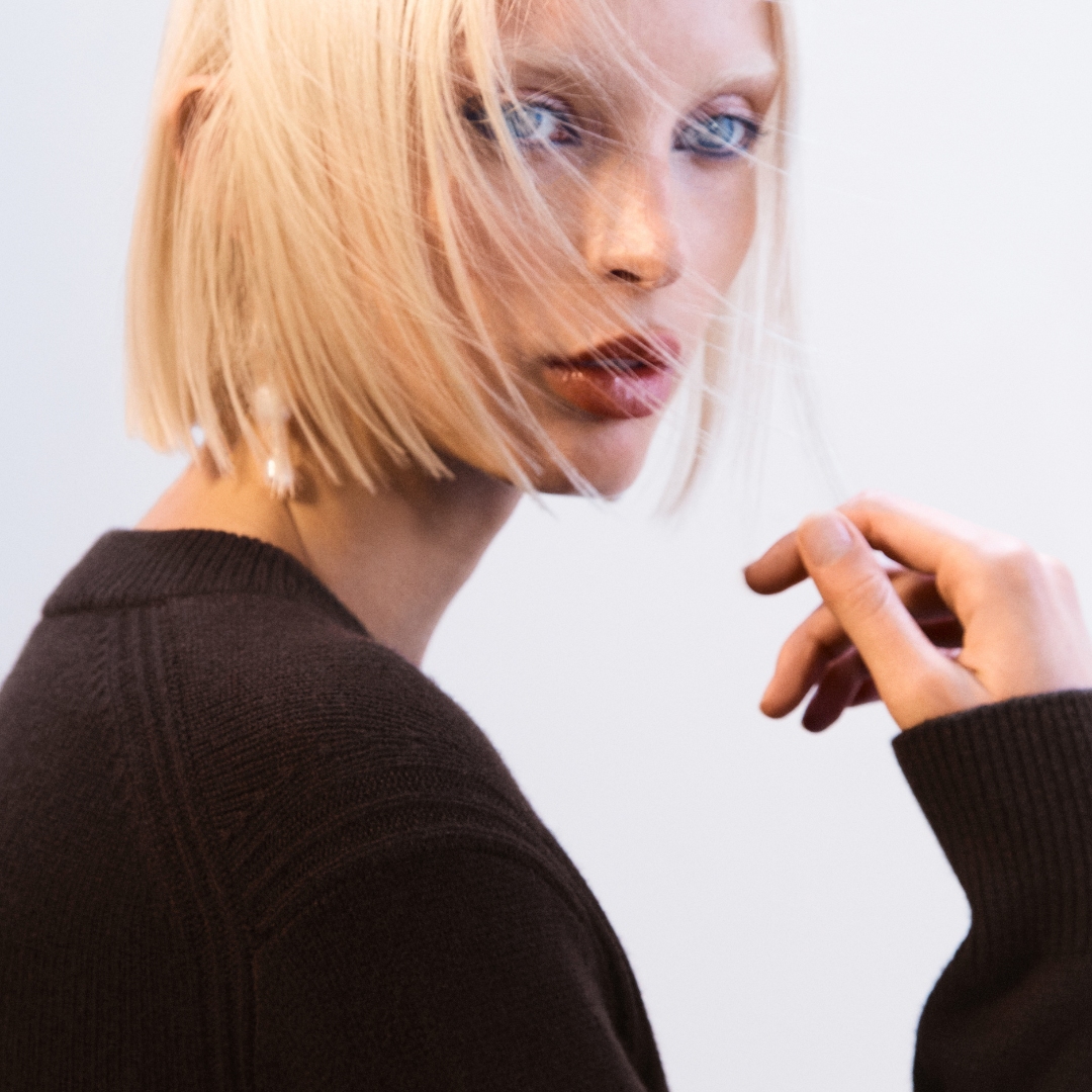 A blond model wearing a cacao brown cashmere pullover from COS