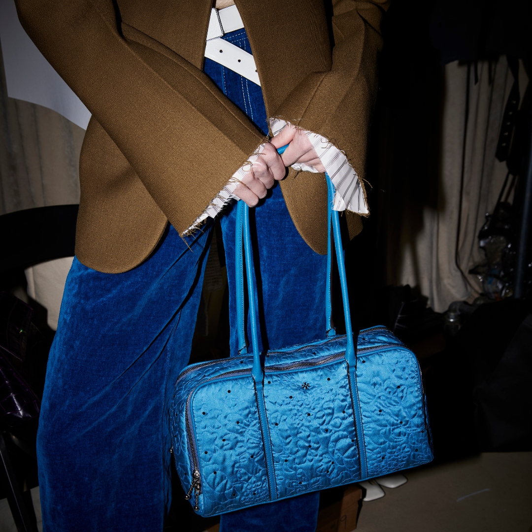 detail of tory burch aw23-24 backstage, model carrying a blue bag