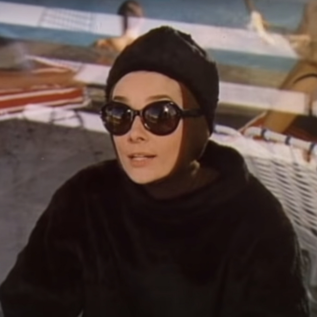 Audrey Hepburn in the film Charade wearing a aprés ski outfit while in a hut on the mountains.