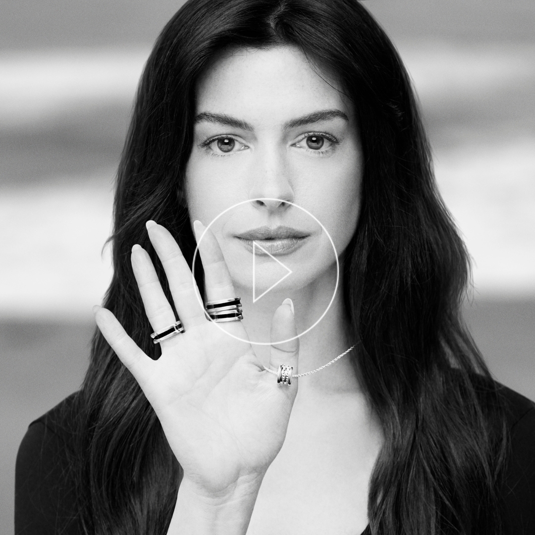 Black and white photo of Anne Hathaway wearing Bulgari's round pendant and rings from the Save the Children collection