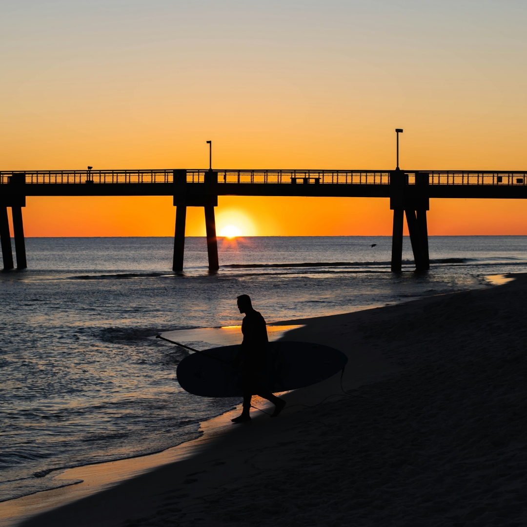 Surfer carrying his surfboard enter in the sea on Okaloosa Island during the sunset
